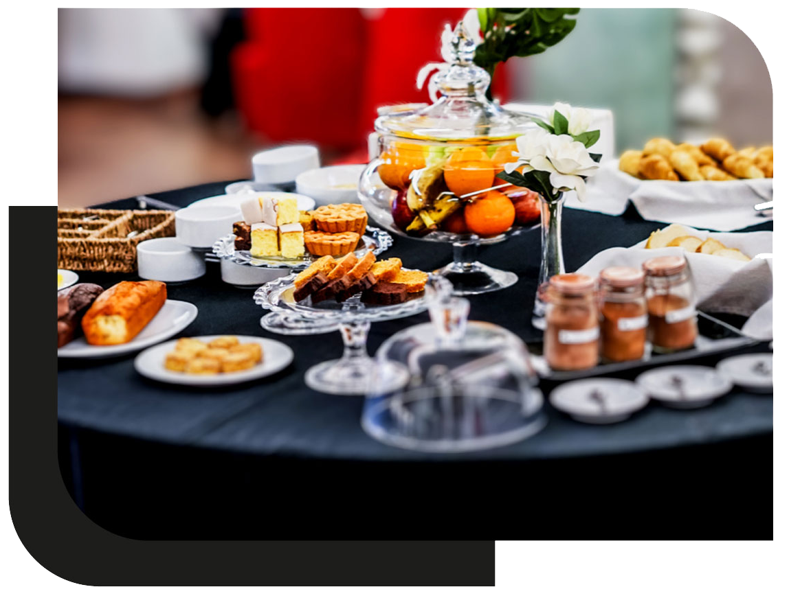 Mesa de desayuno buffet con frutas, panificados, alimentos dulces y salados